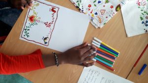 Um aluno a escolher as cores para pintara o seu postal com desenhos inspirados nos lenços dos namorados portugueses