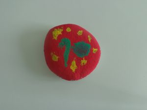 Pedra pintada de vermelho com toques de amarelo e verde