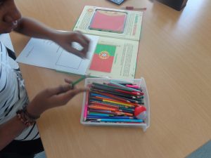 Aluno escolhe lápis de cor para pintar bandeira portuguesa