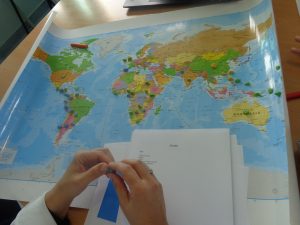 Alunos identificam regiões no mapa-mundi com marcadores coloridos