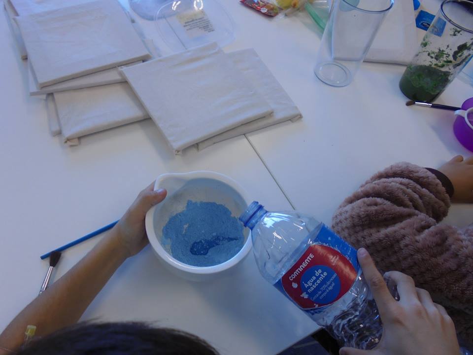 Mãos de aluno a misturar água em pasta azul