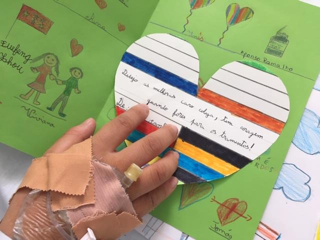 Mão de aluno com cateter e postal