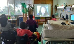 Os alunos ouvem atentamente as palavras da Rita através de videoconferência.