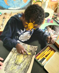 Um aluno pinta a luz do seu coração: muito amarelo sobre uma impressão negra e cinzenta.