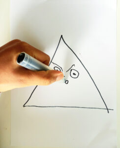 Um aluno elabora o grafismo que lhe calhou para desenhar o nariz da cara que tem a forma de um triângulo.