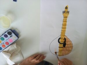 Uma aluna pinta o desenho de uma guitarra portuguesa.