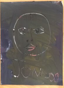 Uma tela na qual o aluno riscou com um pauzinho de madeira o seu autorretrato e nome.