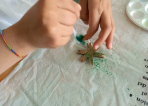 Um aluno pinta uma estrela feita com tiras de rolos de papel higiénico.