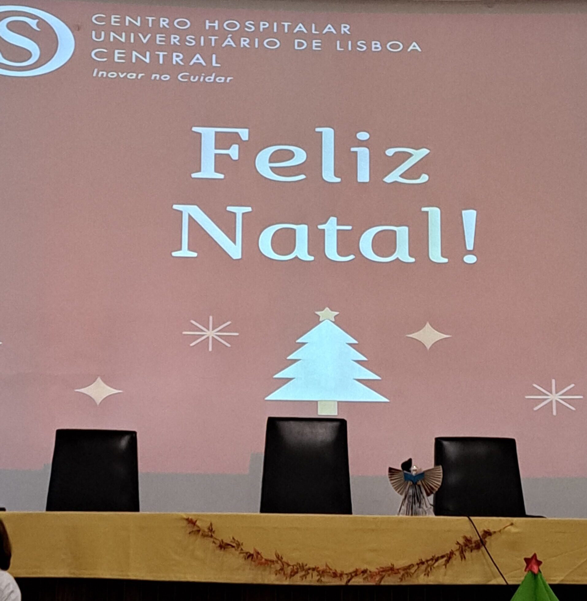 Slide com a mensagem Feliz Natal e motivos natalício (árvore e estrelas estilizadas)