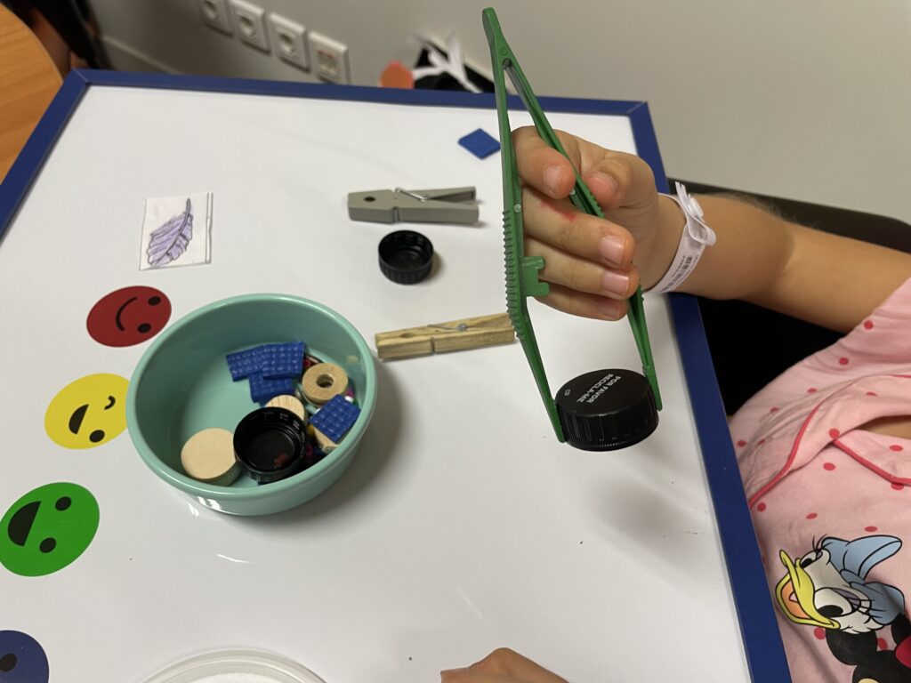 Criança com uma pega a pinçar uma rolha de plástico